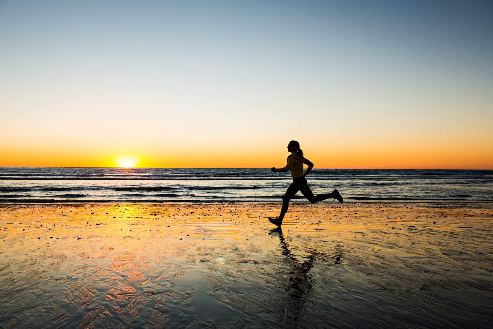 Läuferin am Strand im Sonnenuntergang